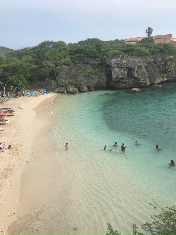 Bucht des Playa Lagung auf Curaçao mit kristallklarem Wasser. Zahlreiche Urlauber baden im Meer.