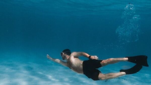 Symbolic image “Curaçao snorkeling”: Man dives under water. He is wearing flippers and diving goggles.