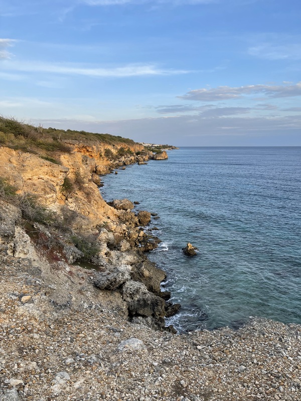 View of Jan Thiel Beach in Curaçao. You can see a slightly rocky path on the left that you can walk along.