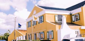 Blick auf das Landhuis Chobolobo auf Curaçao. Das Gebäude hat eine gelbe Fassade und ein blaues Dach.