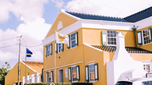 Blick auf das Landhuis Chobolobo auf Curaçao. Das Gebäude hat eine gelbe Fassade und ein blaues Dach.