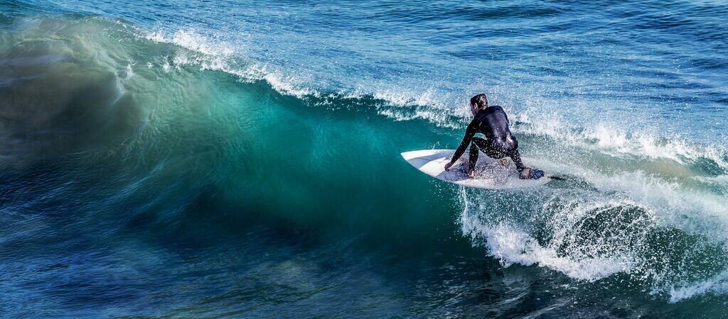 Symbolbild "Surfen auf Curaçao": Surfer reitet eine Welle auf dem offenen Meer.